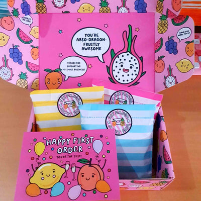 Image shows a Fat Mango packaging box. It is a sturdy, bright and colourful box with fruity puns.